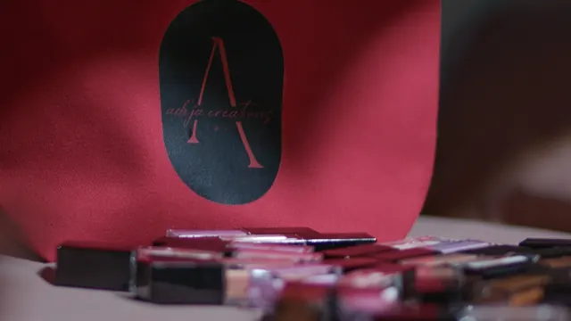 Adeja Creations cosmetics beside a red branded bag.