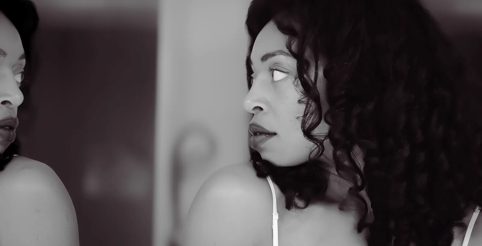Black-and-white profile portrait beside a mirror.