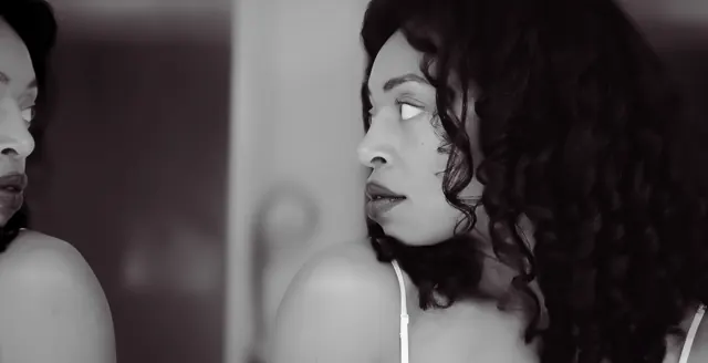 Black-and-white profile portrait beside a mirror.