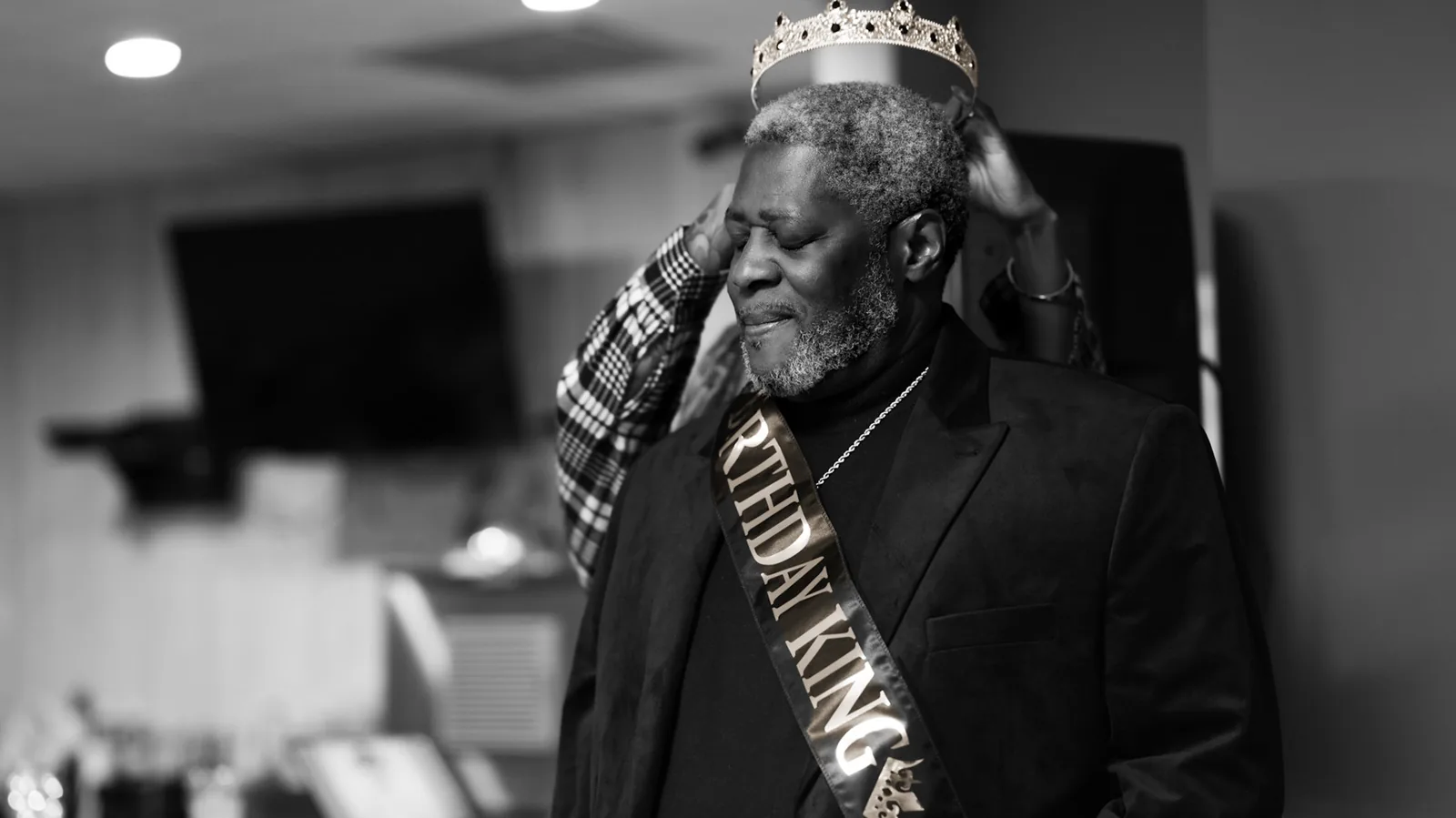 Black-and-white birthday portrait of a man wearing a crown and sash.