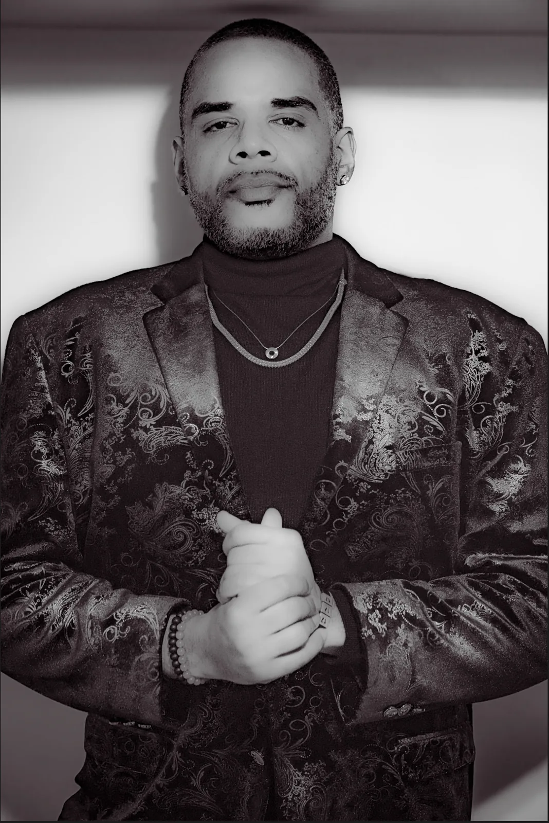Black-and-white portrait of a man adjusting a patterned jacket.