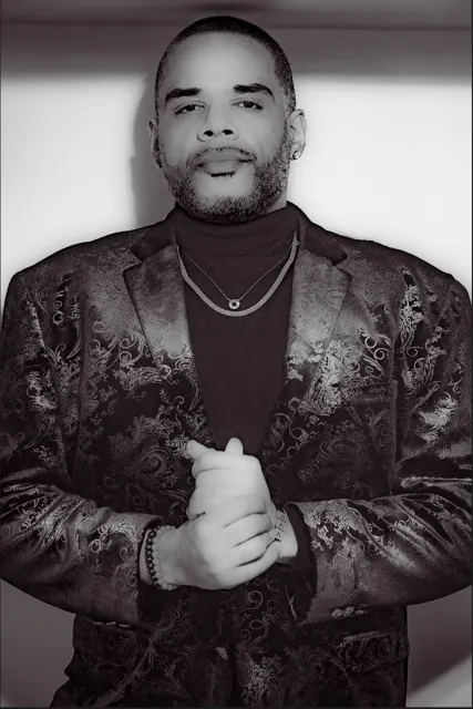 Black-and-white portrait of a man adjusting a patterned jacket.