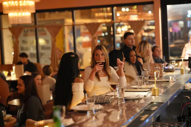 Friends gathered along a warmly lit cocktail bar.