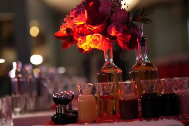 Red roses and cocktails glowing in low light.