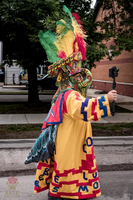 A costumed parade performer in a bright red, yellow and green mask.