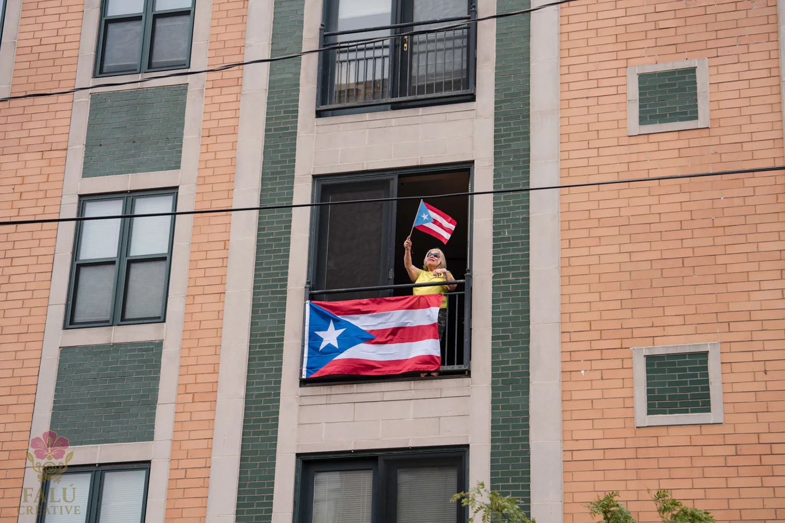 A Puerto Rican flag hanging from an open apartment window.