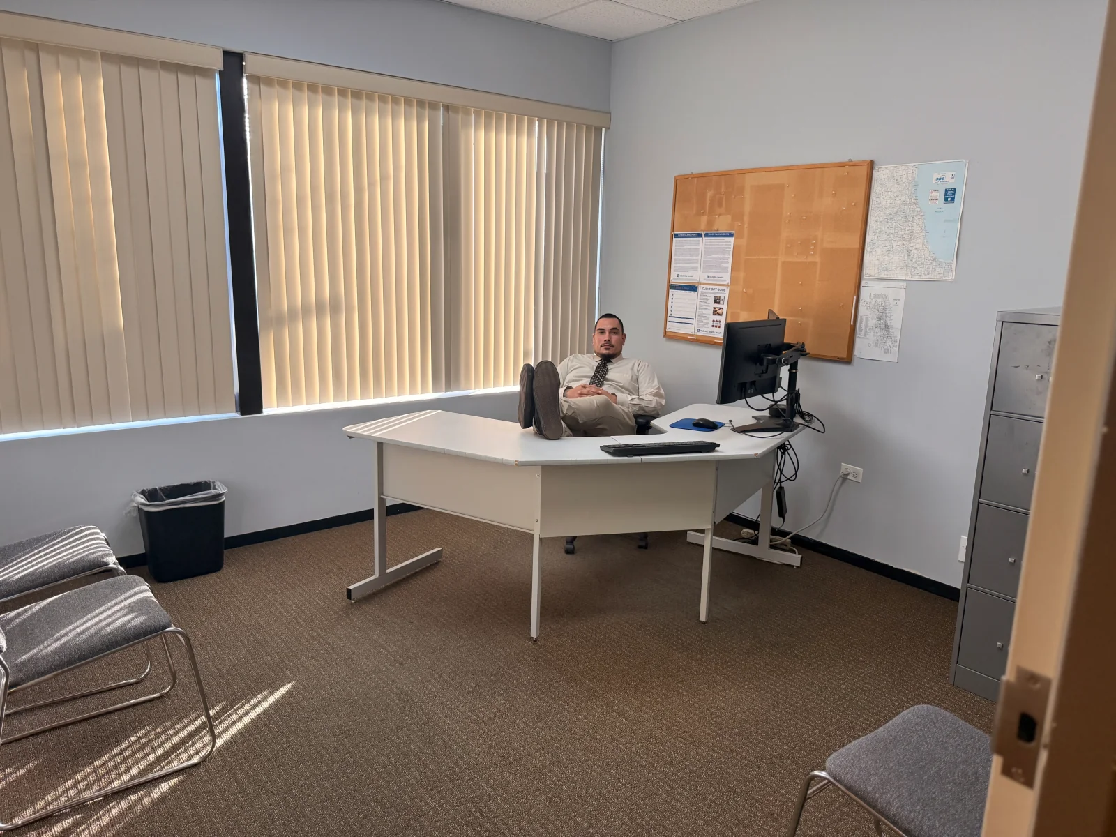 Wide view of Kon seated at a desk in the room where the interview was filmed