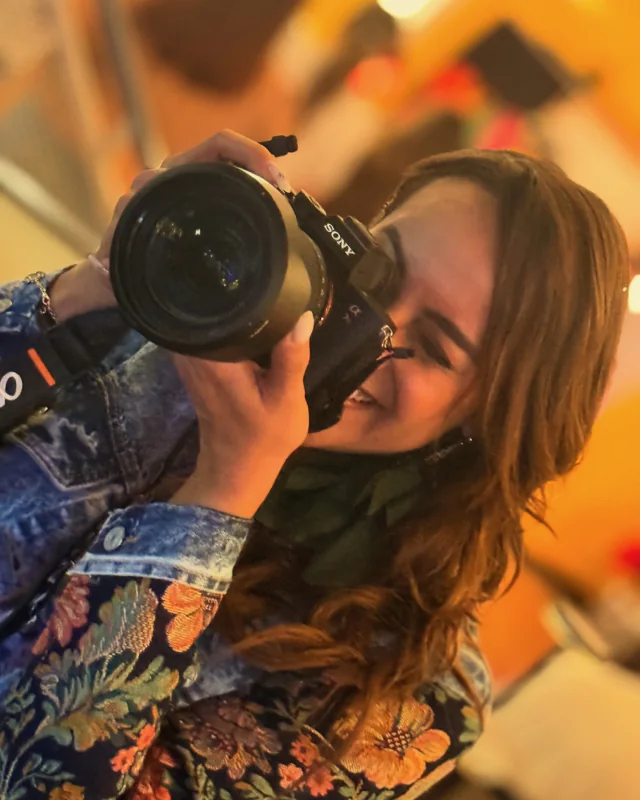 A client in a floral jacket holding Riri to their eye